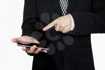 Businessman in Back Suit and Tie Holding Smartphone in Hand And Pointing Finger at Phones Screen Against White Background