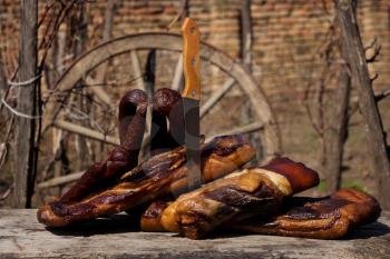 Smoked Bacon and Dried Sausages With Butcher's Knife On A Rustic Wooden Surface. Delicious Domestic Food