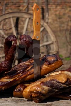 Smoked Bacon and Dried Sausages With Butcher's Knife On A Rustic Wooden Surface. Delicious Domestic Food