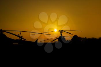 Silhouettes of Helicopters and Planes at the airport at Sunset