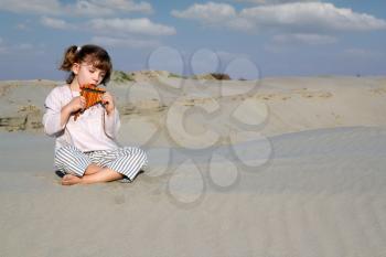 little girl play panpipe in desert