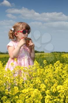 little girl standing in yellow flower field and play pan pipe