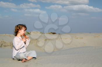 little girl sitting on sand and play music