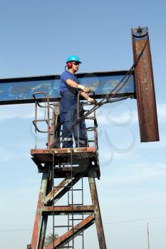 oil worker in blue uniform standing at pump jack