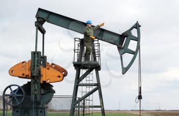 oil worker stands at the pump jack