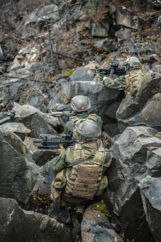 Patrol of norwegian Rapid reaction special forces FSK soldiers in field uniforms in ambush among the rocks guarding perimeter waiting enemy