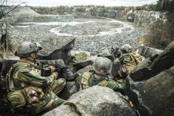 Patrol of norwegian Rapid reaction special forces FSK soldiers in field uniforms in ambush among the rocks guarding perimeter waiting enemy