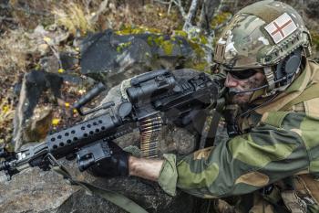 Norwegian Rapid reaction special forces FSK soldier firing among the rocks. High angle foreshortening diagonal view