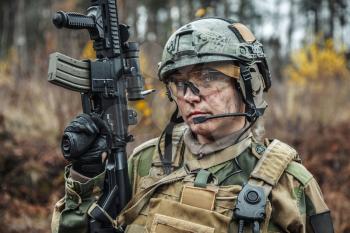 Norwegian Armed Forces Special Command FSK female soldier closeup portrait. Protective eye-wear and assault gun