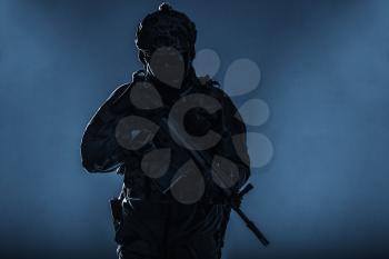 Army soldier in Protective Combat Uniform holding Special Operations Forces Combat Assault Rifle. Studio shot, silhouette