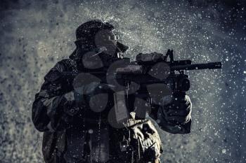 Commando fighter, professional mercenary, special forces soldier with camouflaged face, loaded with ammunition, armed assault rifle, patrolling on secret mission, sneaking in darkness ready to fight