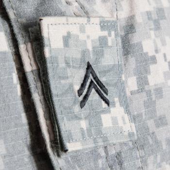 Close up shoot of US army soldiers corporal rank insignia embroidered on army combat uniform collar or lapel patch on hook-and-loop fastener on pixelated grey, universal camouflage pattern fabric