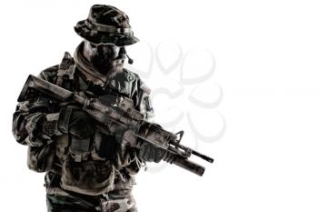 Equipped and armed with service rifle commando fighter, US army special forces soldier, marine rider in camo uniform and boonie hat, looking back, peering around corner studio shoot isolated on white