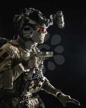 Army special operations soldier, security service fighter, commando shooter equipped modern ammunition, wearing combat helmet, mask and glasses, carefully sneaking in darkness with handgun in hand