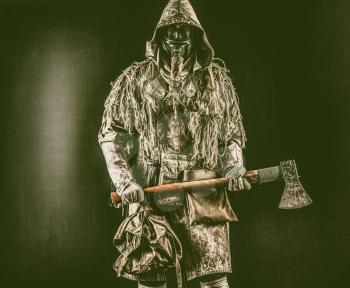 Post apocalyptic survivor, radioactive zone stalker, crazy serial killer or maniac in gas mask and tattered clothes decorated with runes, threatening with raised ax isolated on black studio shoot