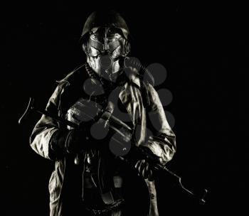 Nuclear post-apocalypse survivor, alternative history nazi soldier or partisan in wool field cap, face gas mask, glasses and handmade armor, with rifle gun studio shoot