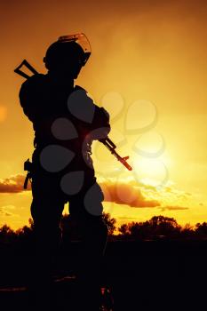 Silhouette of police officer with weapons at sunset