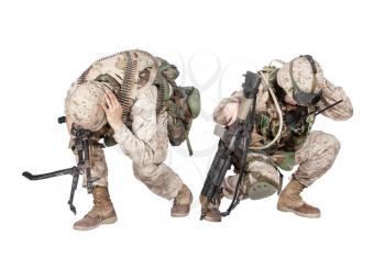 Two army soldiers in camo uniform, armed with assault rifle and machine gun, crouching to ground, holding helmets and covers ears with hands isolated on white studio shoot Grenade or bomb explosion