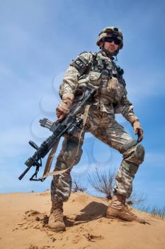 United states airborne infantry man with arms, camo uniforms dress. Combat helmet, knee pads protection wearing, low angle view from below, full body