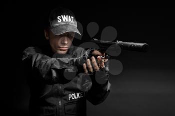 Spec ops police officer SWAT in black uniform with pistol studio 
