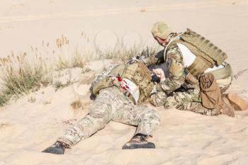 US Army Special Forces soldier medic treating the wounds of injured in the desert