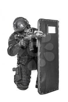 Studio shot of swat police special forces aiming criminals with rifle hiding behind ballistic shield. Isolated on white