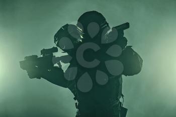 Studio shot of swat police special forces black uniforms aiming terrorists automatic rifle. Tactical helmet vest goggles. Green smoke background