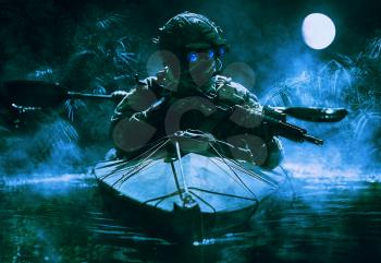 Two special forces operators with night vision goggles paddling in the army kayak in the jungle. Cloudy night, full moon, damp
