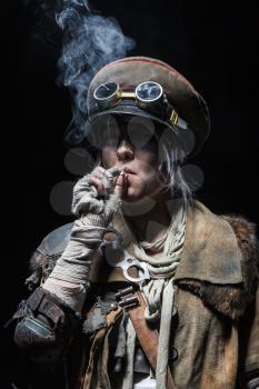 Nuclear post apocalypse life after doomsday concept. Grimy female survivor smoking. Studio closeup portrait on white background