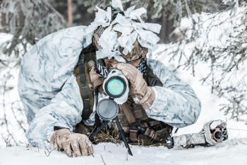 Winter arctic mountains warfare. Action in cold conditions. spotter seeking for enemy in wait somewhere above the Arctic circle