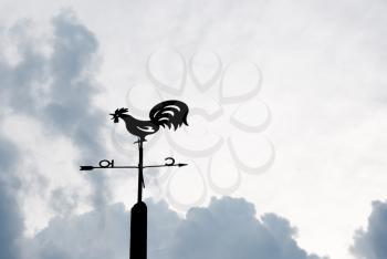 Weather vane against the evening sky and clouds