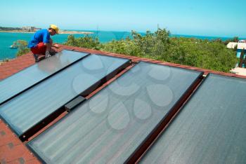 Worker solar water heating panels on the roof.