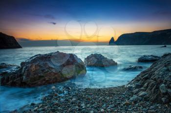 Sunset on the beach with sea, rocks and dramatic sky