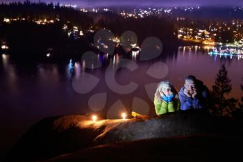 Romantic couple and view of night city with lights, blue dramatic sky. North Vancouver, Canada
