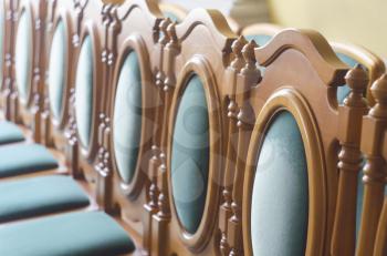 A row of empty baroque style chairs with blue upholstery.