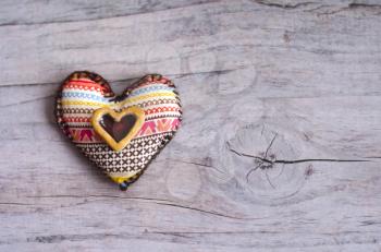 Textile heart of handmade with ethnic ornament on a grayish old aged background. Ceramic heart as an element of decor. Valentine's Day