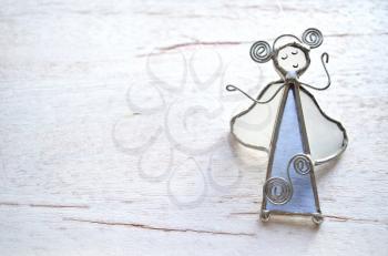 Angel figurine of the glass and wire isolated on wooden background. Abstraction
