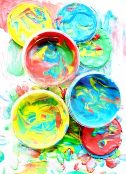Color mixed paint in plastic jars for drawing isolated on white soiled background. Children's creativity. Finger paint. Paint cans with various colors. Background of Multi Colored Paint.