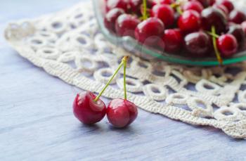 Fresh ripe cherries on wooden table. Cherries in a transparent glass plate and kitchen napkin.
