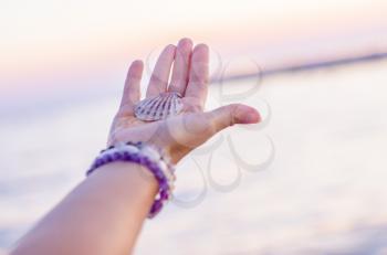 Sea shell on hand against the background of the sea, Relaxation, peace and pleasant mention of the sea.