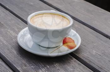 Cup with coffee on a wooden background. Still-life latte with autumn leaves.