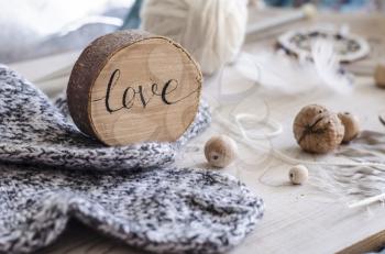 Composition with the inscription Love, wooden and knitted elements. Cozy photo in the style of a hugge.