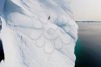 The climber climbs the glacier. Two climbers on an iceberg in the sea.