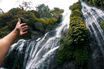 Waterfall in the rain forest. The hand points to the waterfall. Waterfall beauty of nature.