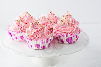 Decorated pink birthday cupcakes  on the cake stand. Sweet dessert  pastry with whipped cream. Birthday homemade cupcakes served for party.