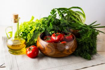 Fresh tomato in wooden bowl and olive oil. Ripe vegetables. Fresh vegetables. Healthy eating concept. Healthy eating. Vegetarian food. 