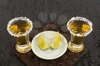 Two gold tequila shots with lime. Tequila shot. Gold Mexican tequila. Tequila