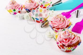 Cookware and pink birthday cupcakes. Birthday cupcake with pink whipped cream. Homemade party cupcakes. 