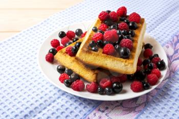 Soft Belgian waffles with blueberry, raspberry and blackcurrant. Breakfast waffles with fresh berries.