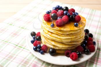 Stack of pancakes with honey, blueberry, raspberry and blackcurrant. Stack of homemade breakfast pancakes served with fresh berries. 